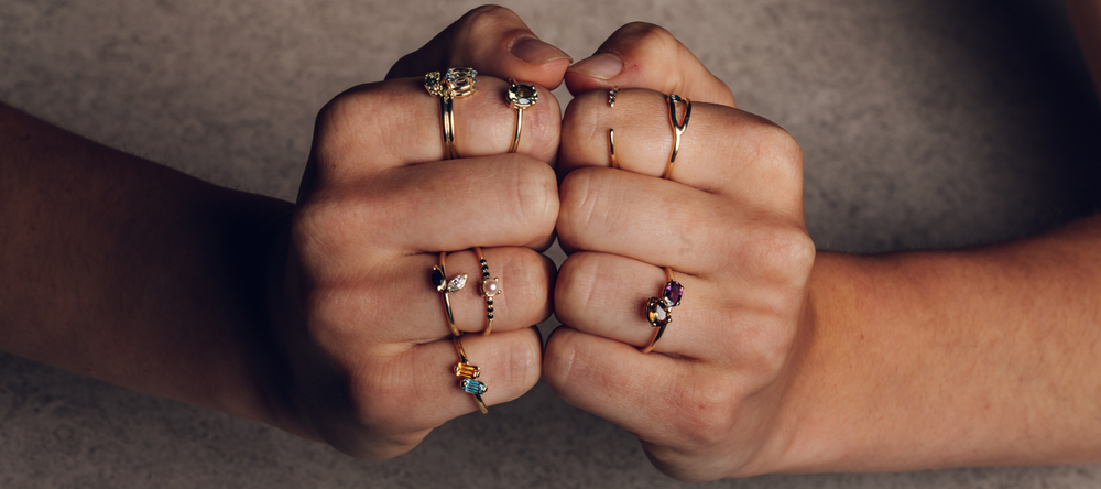 hands with stacked golden rings with diamonds and gemstones